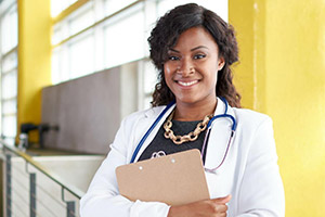 Female doctor smiling and holding patient clipboard